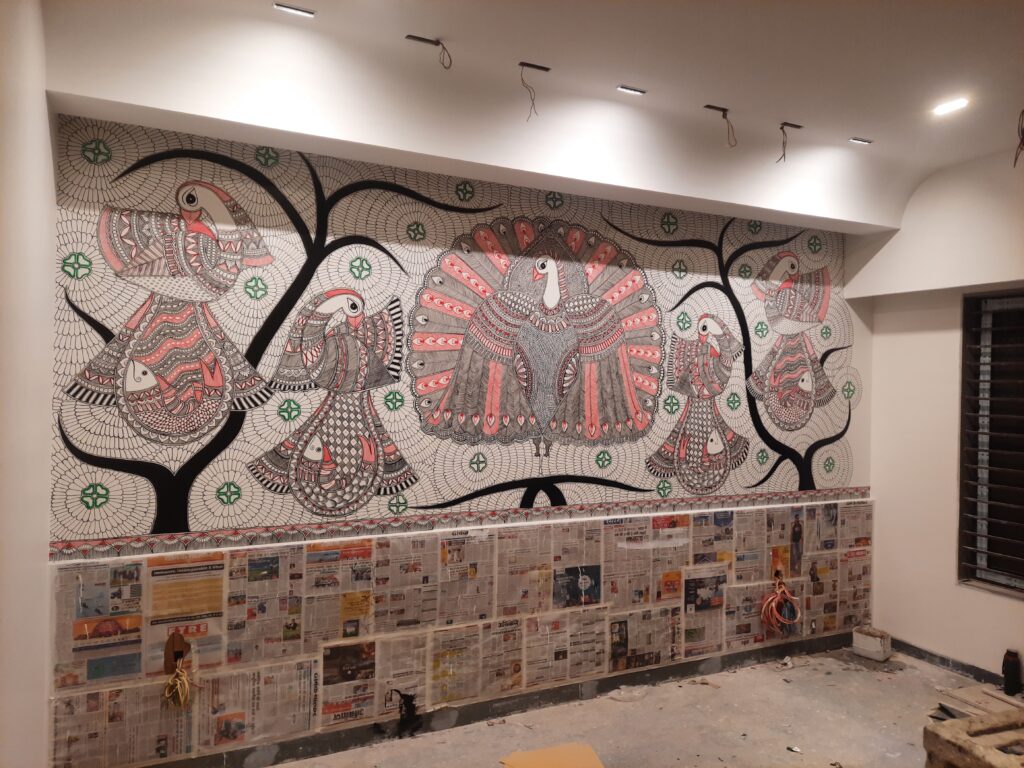 Residential interior featuring handcrafted Madhubani art wall and counter border by Yuvarti Craft Studio, showcasing traditional Indian folk painting style.